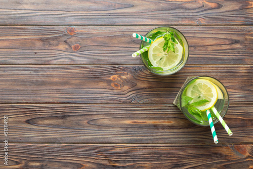 Caipirinha, Mojito cocktail, vodka or soda drink with lime, mint and straw on table background. Refreshing beverage with mint and lime in glass top view flat lay