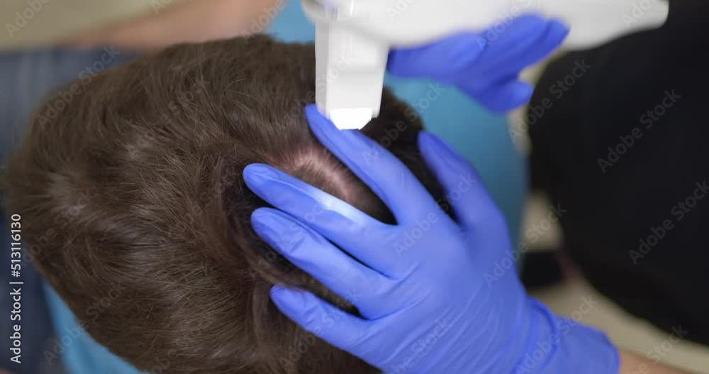 Trichologist working with client at personal office, closeup. Examining scalp using dermatoscope