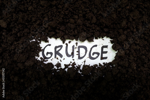 Bury grudge and stop holding concept. Grudge text word on soil backdrop. photo