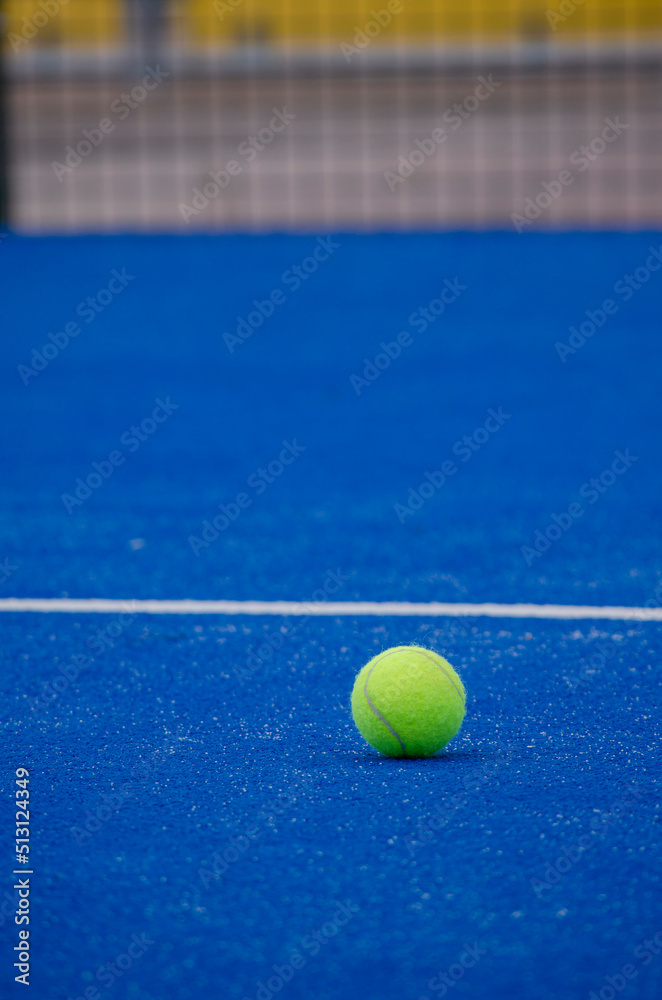 a paddle tennis ball on a blue artificial grass court, racket sports concept
