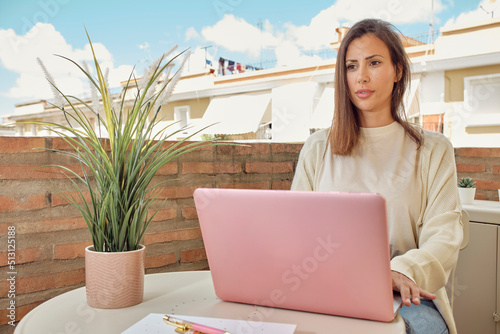 young woman working on the terrace of her house with her laptop and smartphone