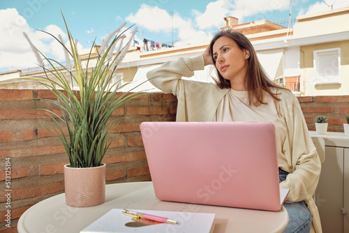 young woman working on the terrace of her house with her laptop and smartphone