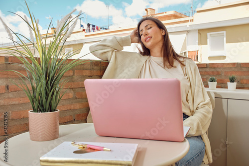 young woman working on the terrace of her house with her laptop and smartphone