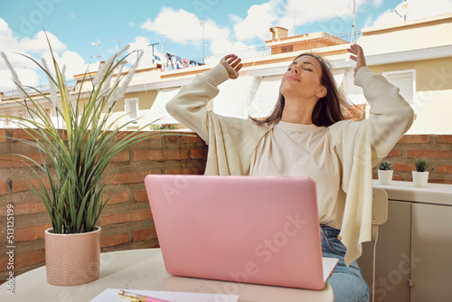young woman working on the terrace of her house with her laptop and smartphone