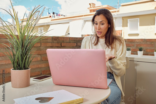 woman on the terrace of her house making a video call with her laptop