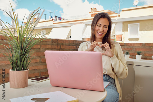 woman on the terrace of her house making a video call with her laptop