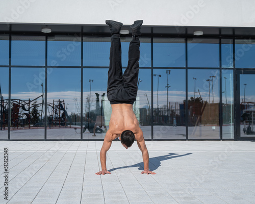 Fotografia A man doing a handstand outdoors against of panoramic windows.