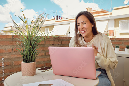 woman on the terrace of her house making a video call with her laptop