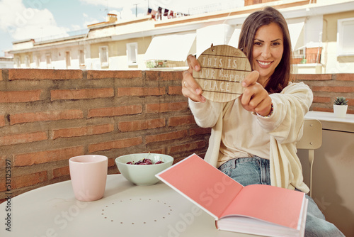 Beautiful and young woman relaxing on the terrace of her house reading and eating cherries.