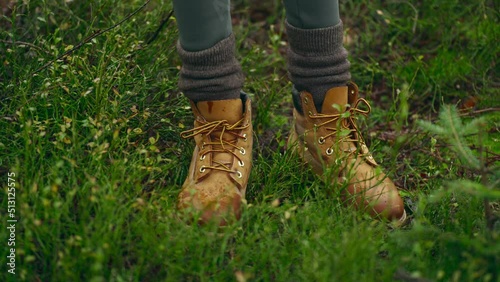 closeup womans hikers foots in yellow hiking boots walks outdoors in wet green autumn forest in bushes between firs. person in wild nature, faceless. travel and vacation, holiday hike photo