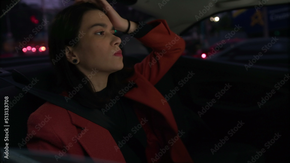 Passenger in car backseat checking cellphone at night riding in urban city. Young woman looking at smartphone device commuting from work Passenger in car backseat checking cellphone at night riding in urban city. Young woman looking at smartphone device commuting from work