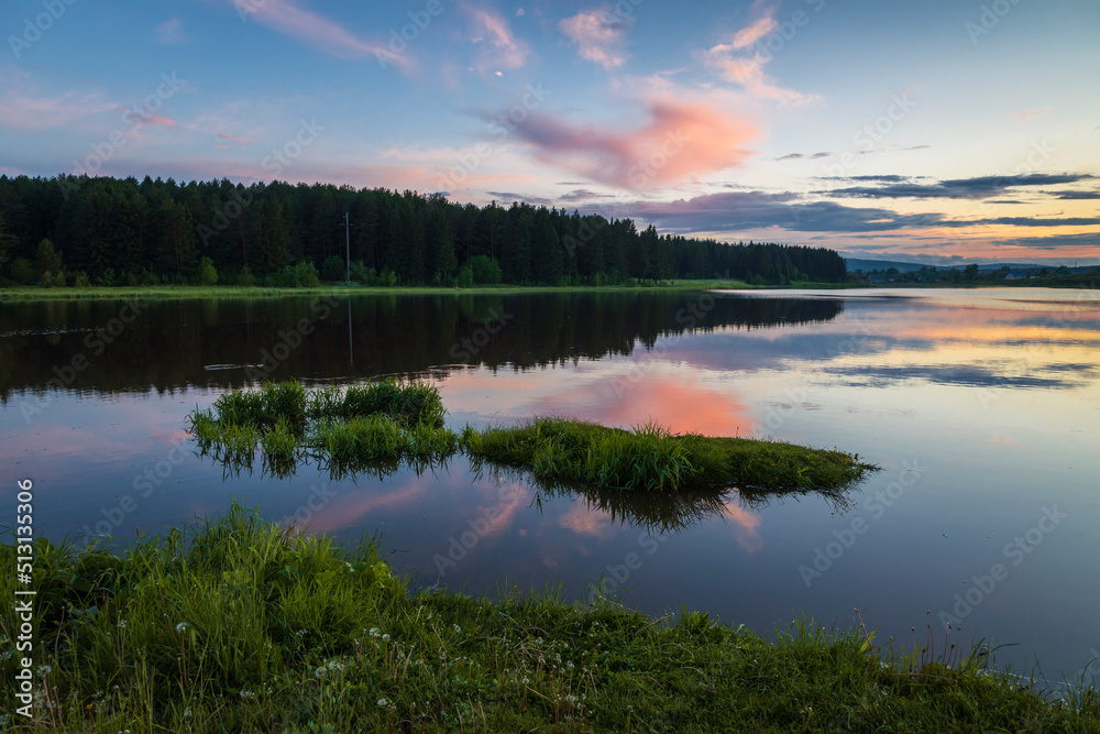 A beautiful sunset landscape of the countryside with a lake and reflection in the water.