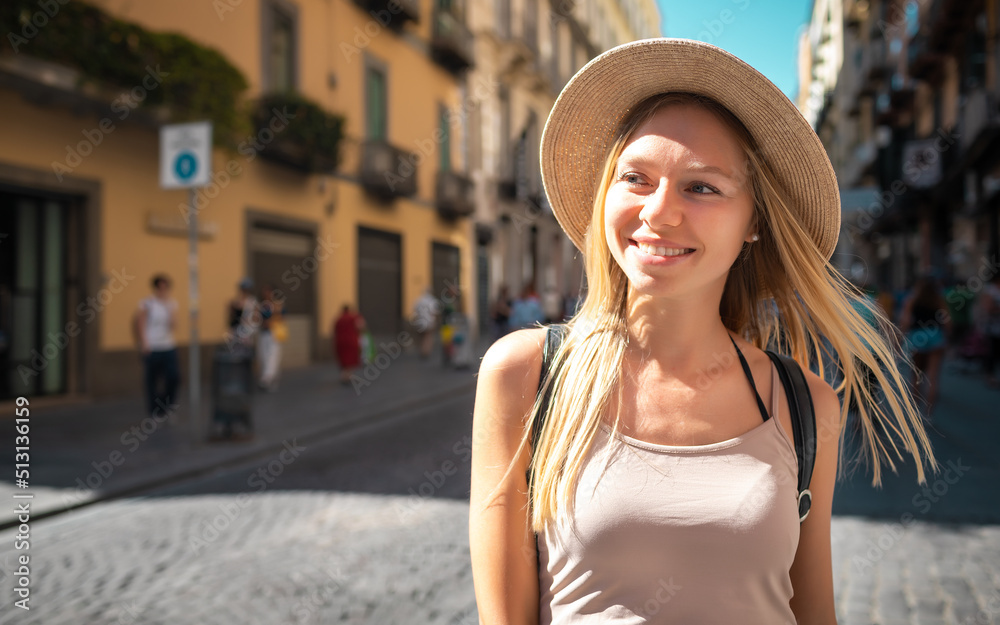 Young attractive smiling girl tourist in hat exploring new Europe city at summer holiday