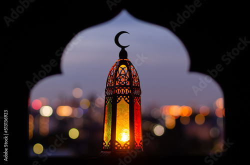 Lantern that have moon symbol on top with blurred focus of paper cut for mosque shape background. Ramadan Kareem and Islamic new year concept.