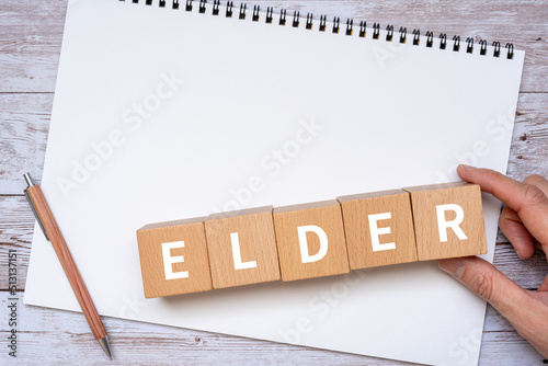 年上・年長者のイメージ｜「ELDER」と書かれたブロック、ノート、ペン、手