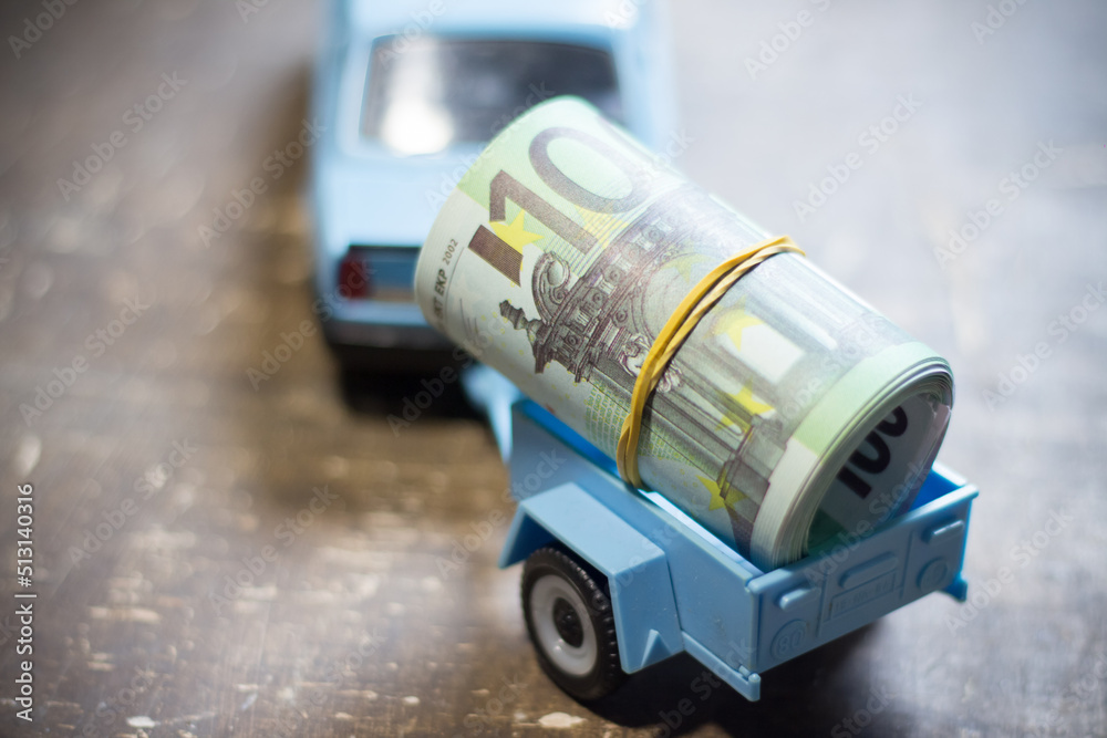 Toy car with banknotes in the trailer. Rise in the cost of fuel due to the war in Ukraine