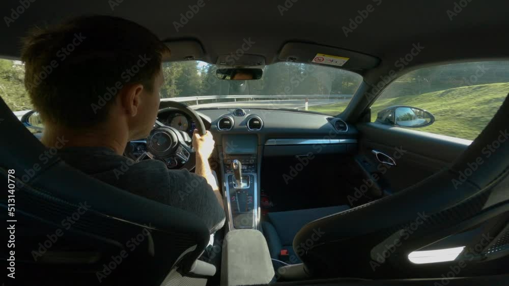 GIAU PASS, DOLOMITES, ITALY, MAY 2022: Young male driver driving through bends on a serpentine road over mountain pass. Exploring beautiful alpine world in spring while travelling on panoramic roads. GIAU PASS, DOLOMITES, ITALY, MAY 2022: Young male driver driving through bends on a serpentine road over mountain pass. Exploring beautiful alpine world in spring while travelling on panoramic roads.