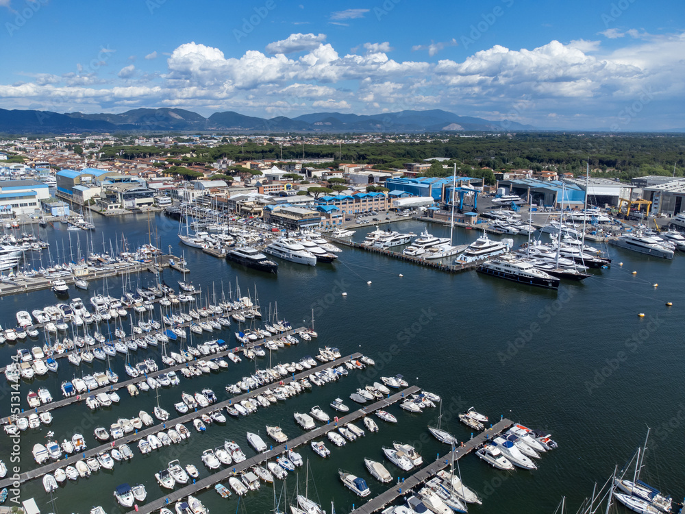 Drone view of many boats moored at Viareggio, Italy with mountains and dramatic clouds.