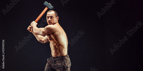 Billede på lærred Muscular man with great anatomy posing on a black background with a big hummer i