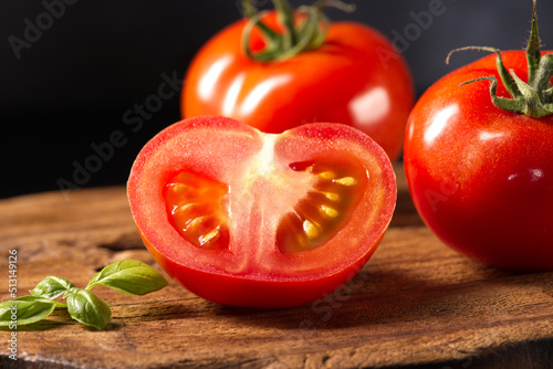 Red cut tomato on a wooden board.