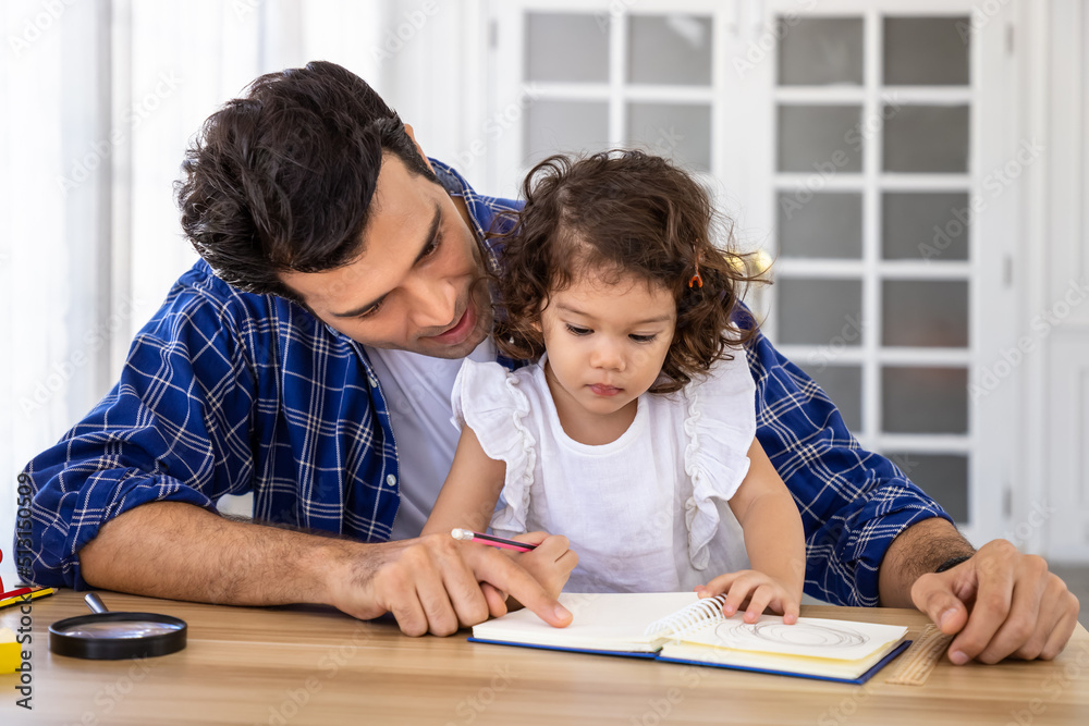 Caucasian handsome man father teach cute young preschool Caucasian child girl daughter to draw and write with pencil at desk Caucasian handsome man father teach cute young preschool Caucasian child girl daughter to draw and write with pencil at desk