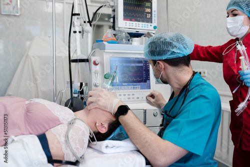 Anesthetist observes the monitor on the ventilator while the patient is being anesthetized. Anesthesiologist gives anesthesia to female patient before operation in a clinic.