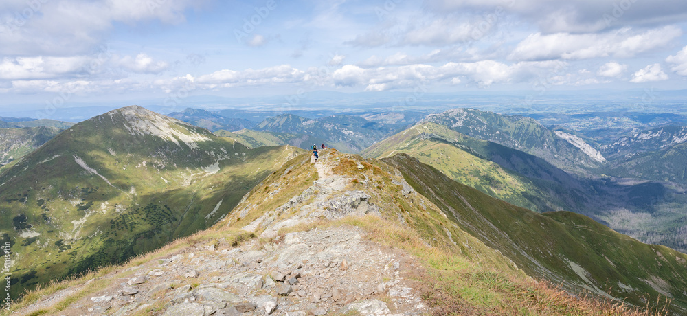 Alpine panorama with mountain ranges and hiker going through them on a sunny day, Slovakia, Europe