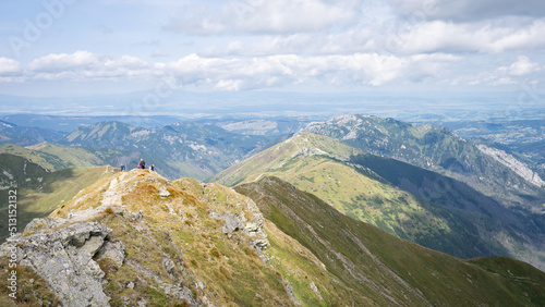 Alpine vista with mountain ranges and hiker going through them on a sunny day, Slovakia, Europe