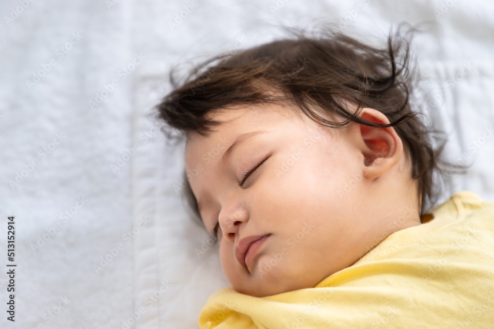 Little Asian baby girl lying down sleeping on bed at home. Newborn child relaxing in bed. Nursery for young children. Little Asian baby girl lying down sleeping on bed at home. Newborn child relaxing in bed. Nursery for young children.