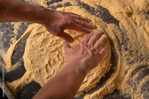 Making pizza dough. Hands kneding a dough for a pizza cooking with flour on the table photo