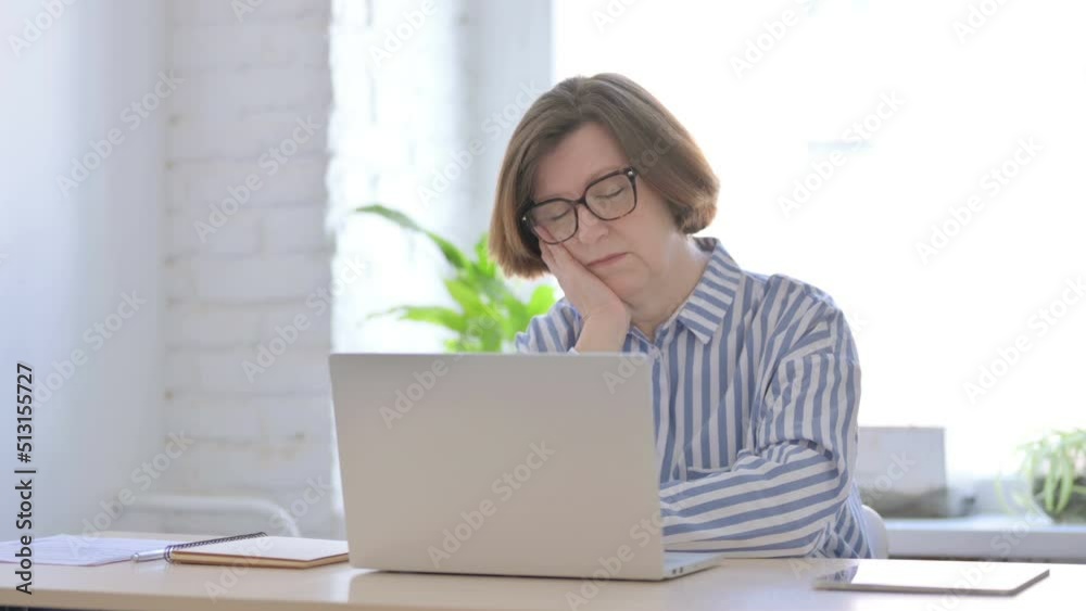 Senior Woman Sleeping While Sitting in Office with Laptop Senior Woman Sleeping While Sitting in Office with Laptop