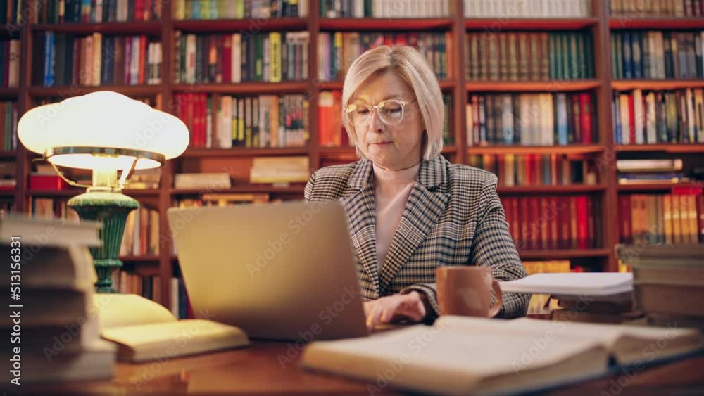 Woman working on laptop late in the evening, scientific researcher in library Woman working on laptop late in the evening, scientific researcher in library