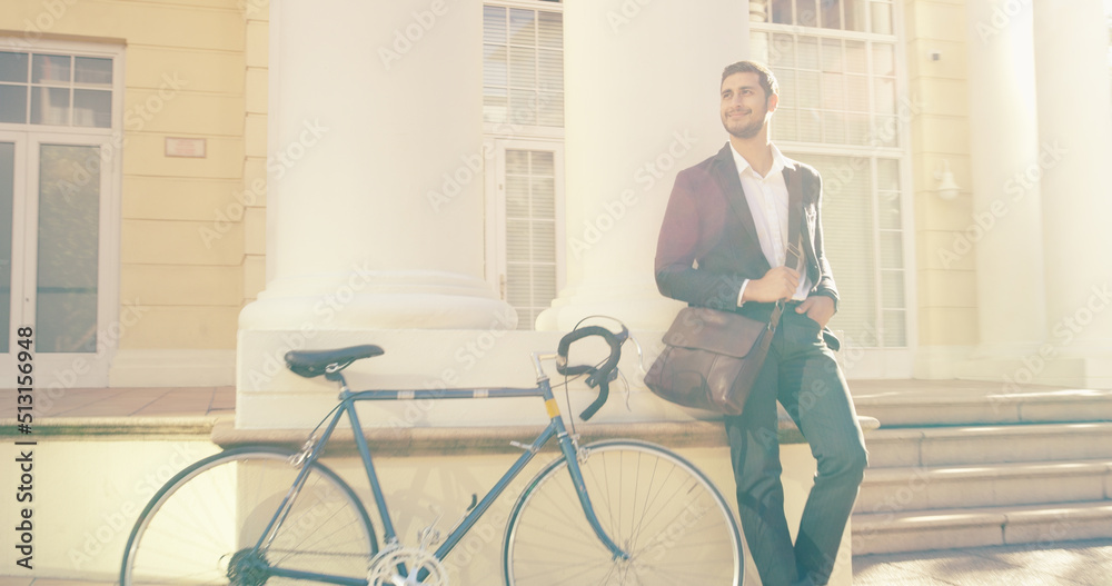 Catching some sunshine before he checks into the office. Shot of a handsome young businessman posing next to a bicycle in the city. Catching some sunshine before he checks into the office. Shot of a handsome young businessman posing next to a bicycle in the city.