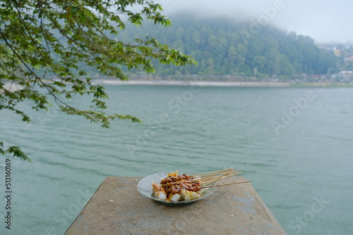 A plate of satay meat on a lake background
