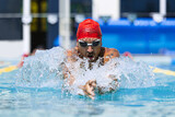 One muscular man, professional swimmer in goggles training at public swimming-pool, outdoors. Sport, power, energy, style, hobby concept.