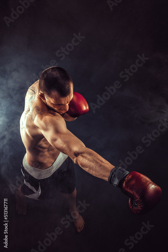 Muscular kickbox or muay thai fighter punching in smoke © zamuruev