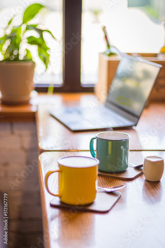 Obraz na płótnie Coffee cups and laptop on the table in cafe. Coffee break. Idyllic place for work. Freelance work place. Morning with coffee and notebook. Cafe interior. Creative space for work. Hot morning drinks. w salonie