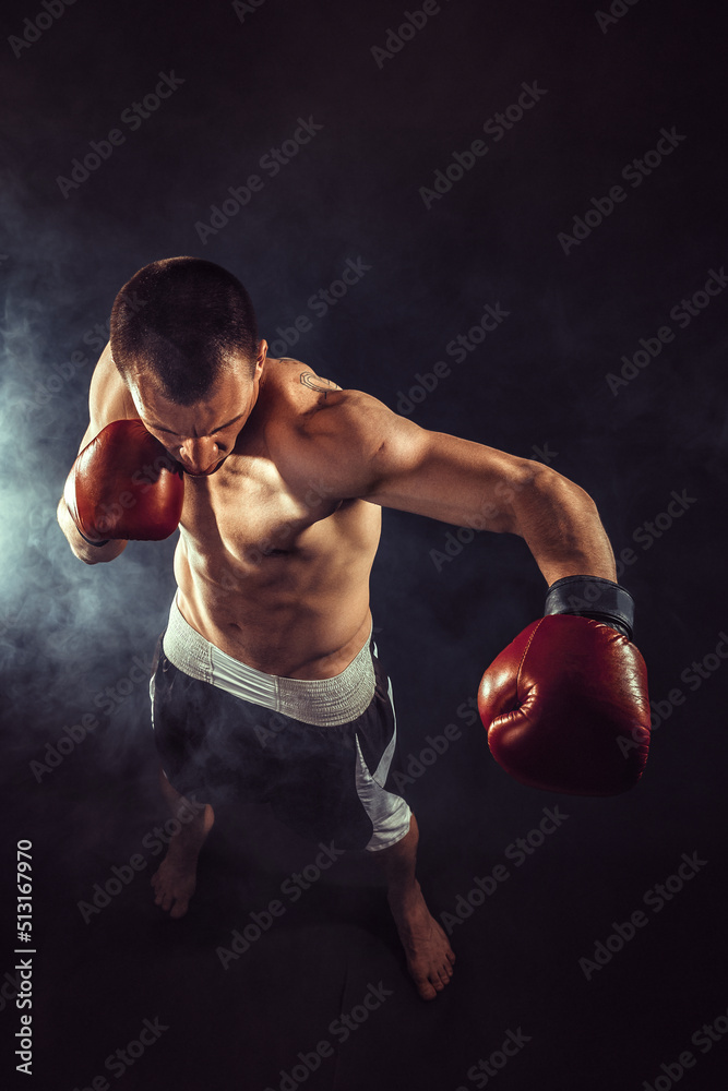 Muscular kickbox or muay thai fighter punching in smoke Muscular kickbox or muay thai fighter punching in smoke