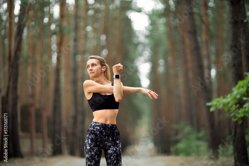 Women stretching arms and breathing fresh air in middle of pinewood forest while exercising. Workouts and Lifestyles concept. Happy life and Healthcare theme. Nature and Outdoors theme