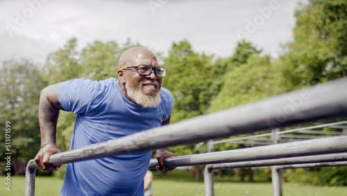 Senior black male doing tricep dips on bars outdoors
