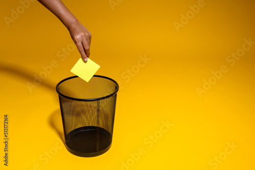 Fotografie The hand throws a yellow sticker into the trash