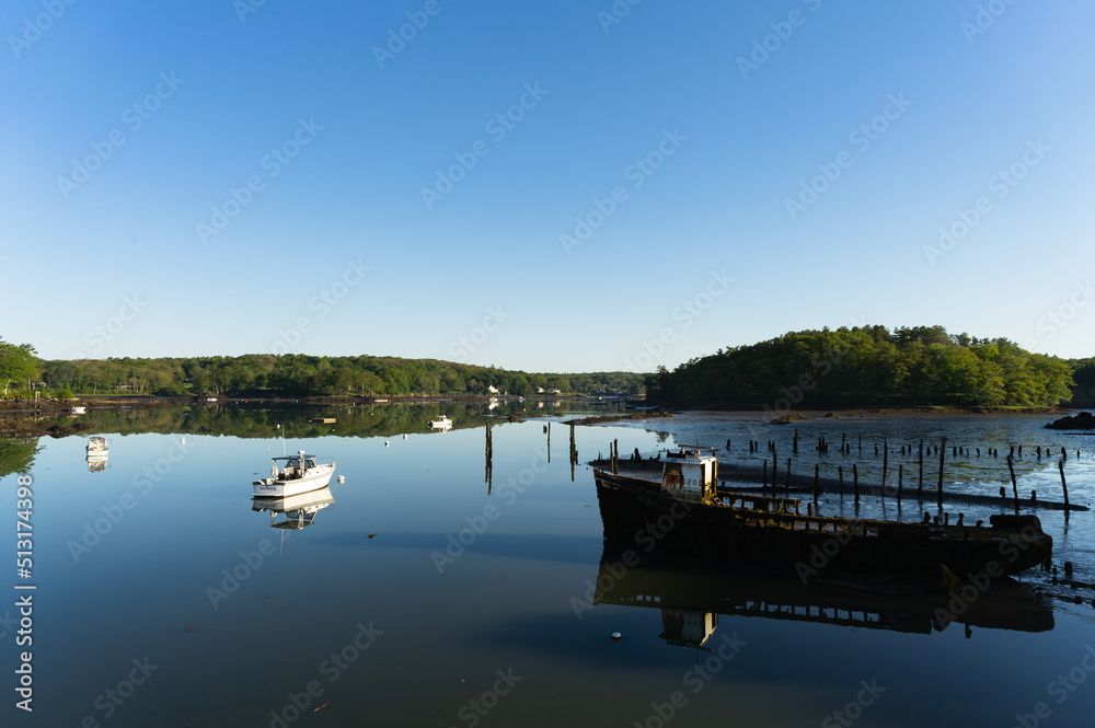 A landscape view of fishing boats in an estuary at low tide during sunrise in Maine