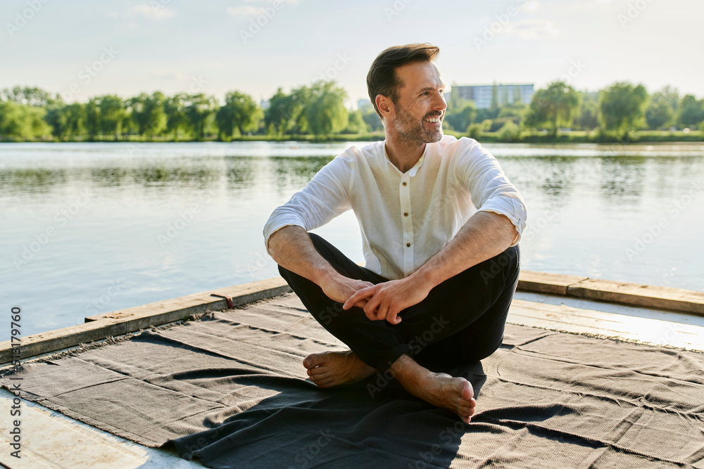 Portrait of a handsome man sitting on a deck by a lake on a summer afternoon Portrait of a handsome man sitting on a deck by a lake on a summer afternoon