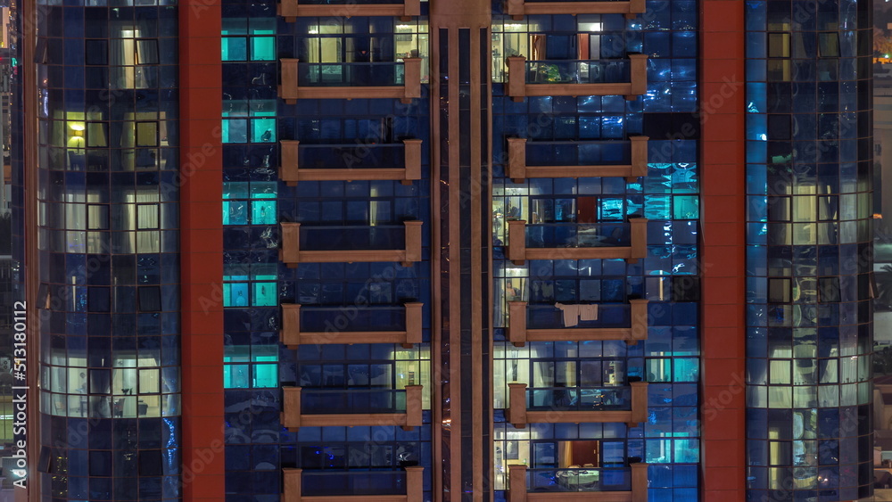 Night aerial view of apartment building glass window facade with illuminated lighted workspace rooms timelapse.