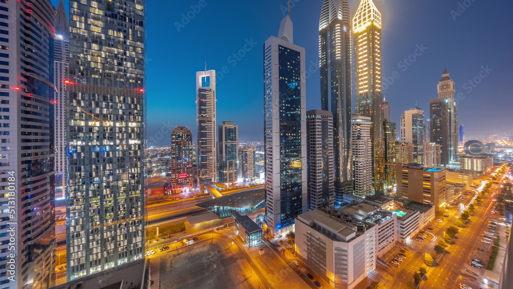 Fototapeta premium Aerial view of Dubai International Financial District with many skyscrapers day to night timelapse.