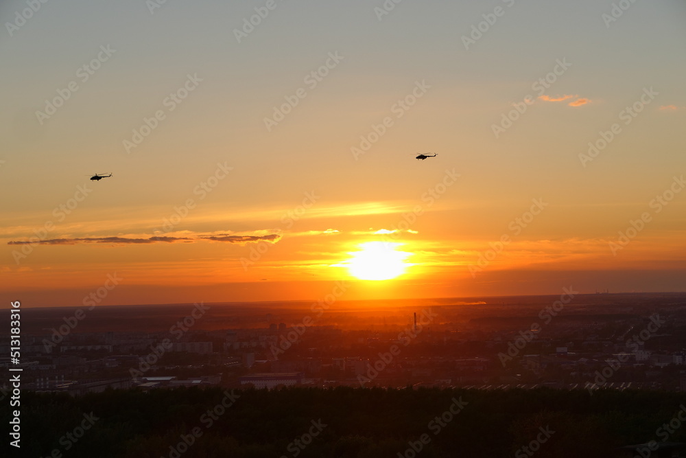 Two helicopters in the sky against the backdrop of the setting sun, Bright sunset