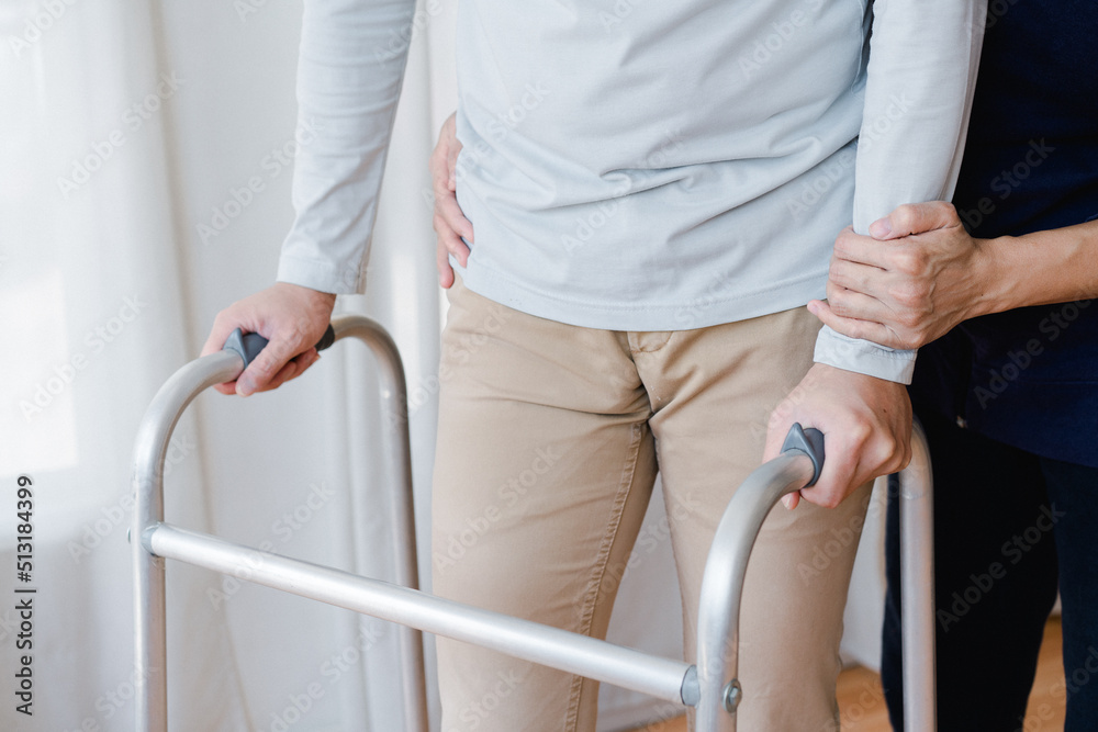 Cropped view of elderly man walking with frame at home, closeup. young male asian using medical equipment to move around his house. Enable older person in need of professional help