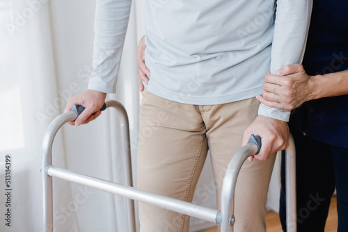 Cropped view of elderly man walking with frame at home, closeup. young male asian using medical equipment to move around his house. Enable older person in need of professional help