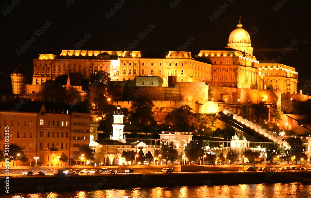 Hell beleuchteter Burgpalast am Ufer der nächtlichen Donau