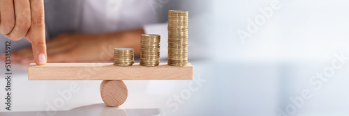 Businessperson Balancing Coins On Wooden Seesaw photo